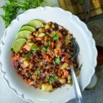 A bowl full of black chickpea, potatoes, vegetables and tamarind sauce.