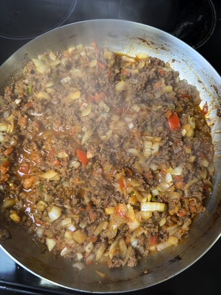 ground beef is cooked with spices, onion and tomatoes