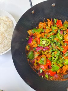 A bowl full of chicken jalfrezi served with white rice