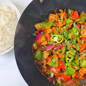 A bowl full of chicken jalfrezi served with white rice